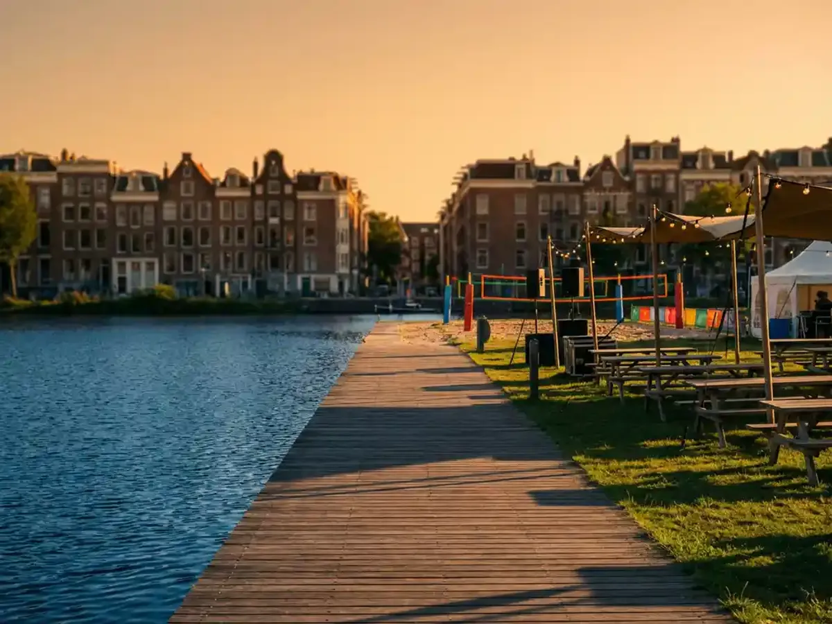Houten steiger met beachvolleybalvelden en picknicktafels aan Amsterdamse gracht tijdens gouden uurtje