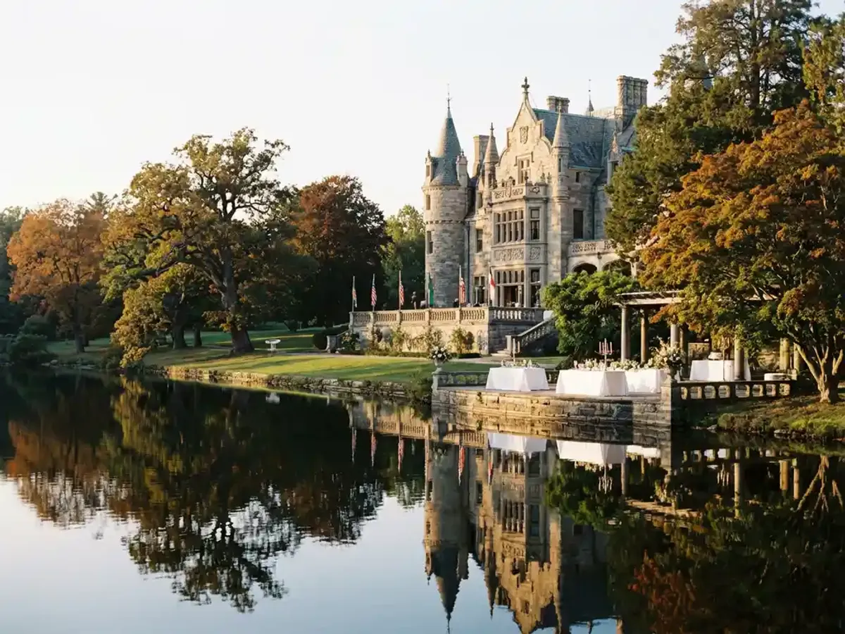 Historisch kasteel met stenen torens weerspiegeld in stil meer, elegant terras met witte linnen gedekt voor intieme bijeenkomst