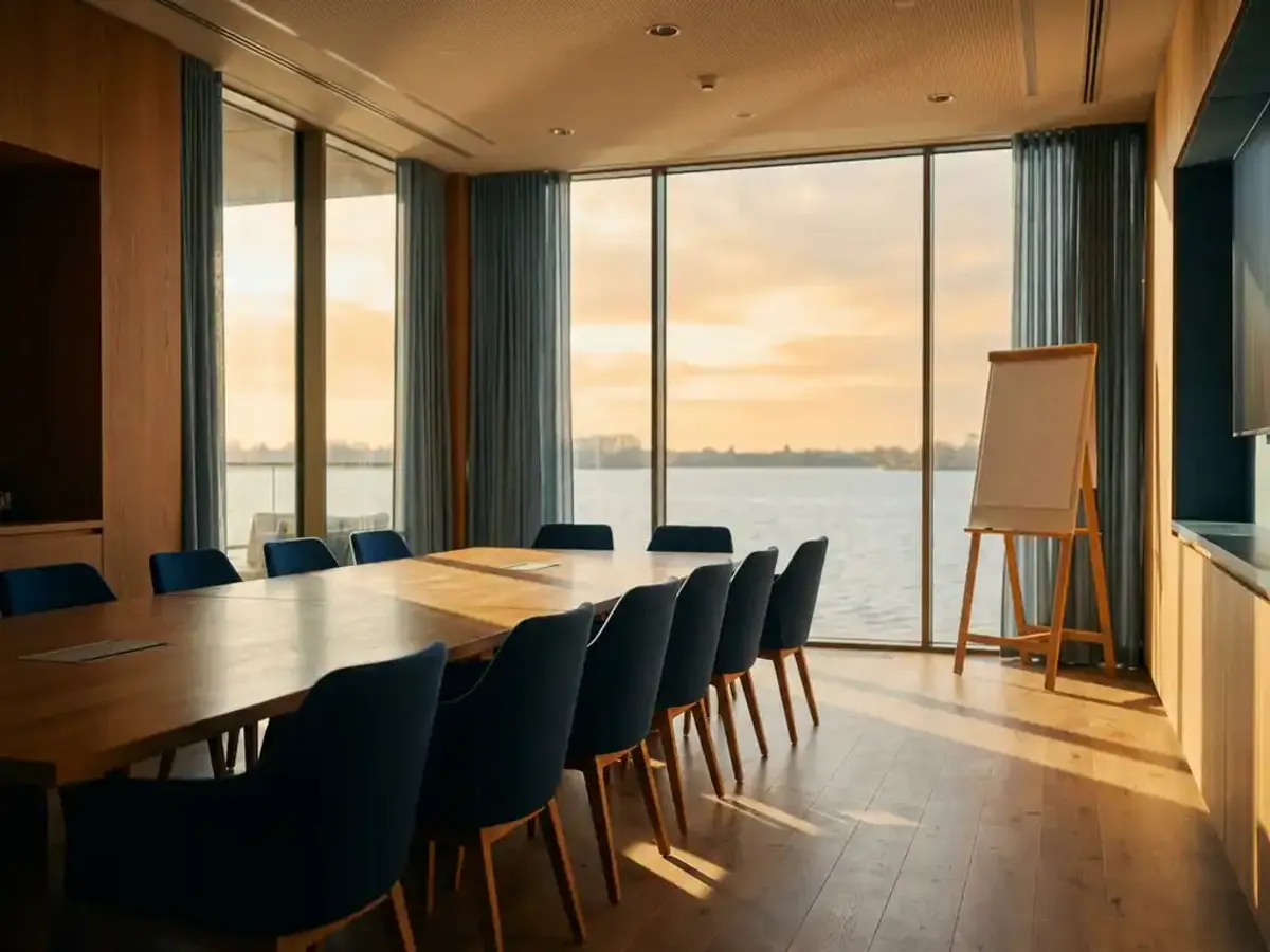 Moderne vergaderzaal met houten tafel en lege stoelen, vloer-tot-plafond ramen met uitzicht op het Eemmeer, natuurlijk zonlicht